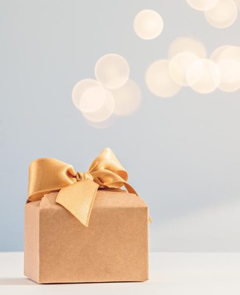 A gold box tied with a gold bow ribbon against a pale blue background.
